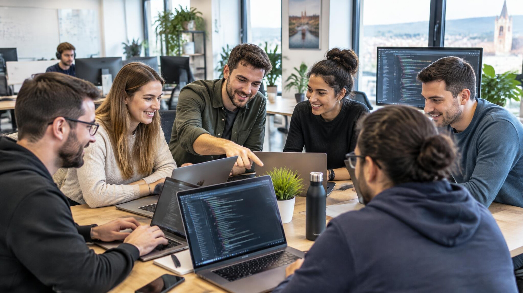 Team of software developers collaborating around laptops in a bright office